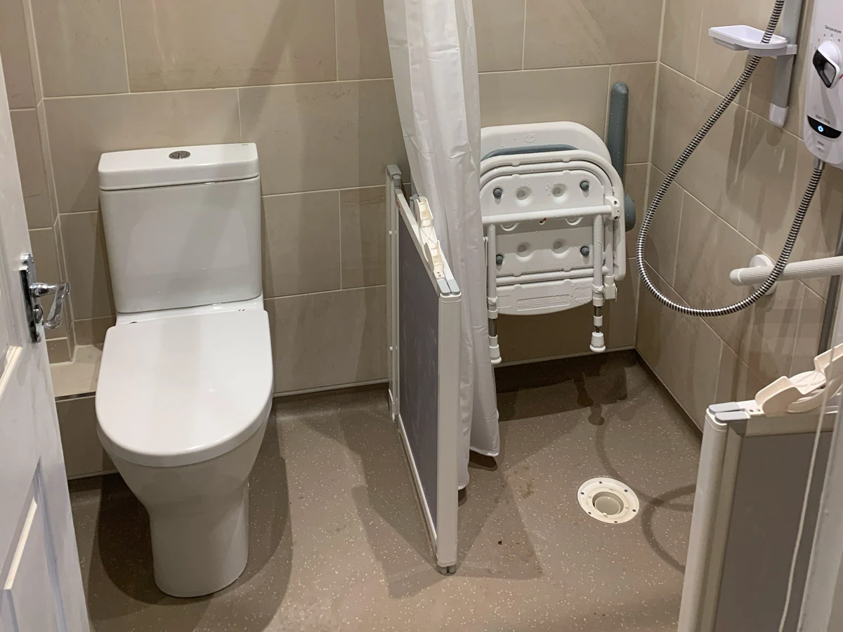A white toilet sitting next to a shower in a bathroom.